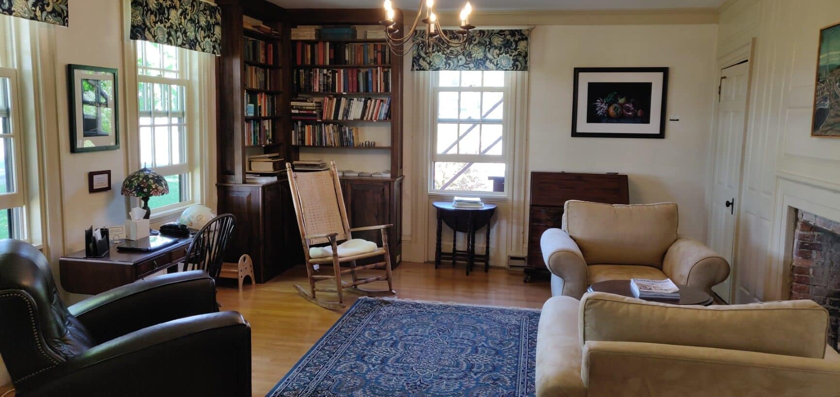 View of room with large bookshelves, lots of chairs, and windows